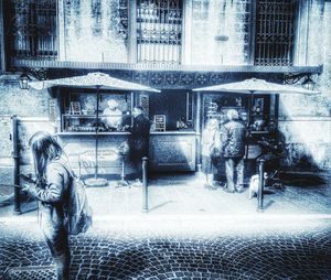 Digital composite image of people walking on street by building