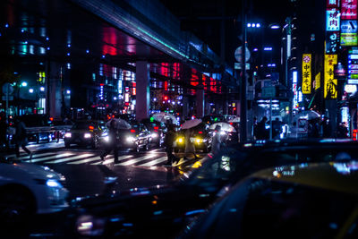 Road amidst illuminated buildings against sky