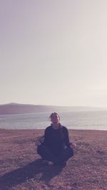 Woman in lotus position sitting on sand at beach