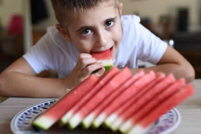 Portrait of boy eating watermelon at home
