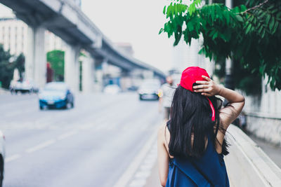 Rear view of woman with umbrella standing in city