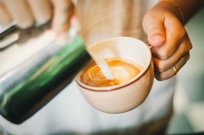 Close-up of hand pouring milk in cup