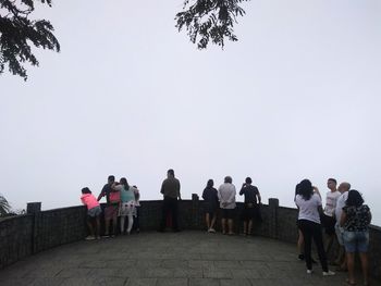 Rear view of people walking against clear sky