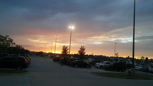 Cars parked in parking lot against dramatic sky