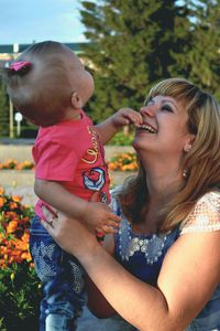 Happy mother playing baby girl at park