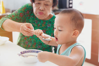 Grandmother feeding grandson at home