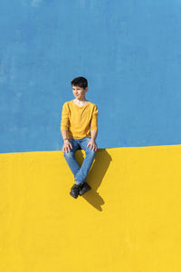 Full length of boy sitting against wall