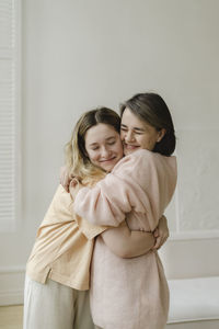 Happy mother and daughter embracing in living room