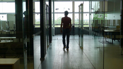 Rear view of man walking in glass building