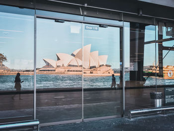 Buildings by sea against sky seen through glass window
