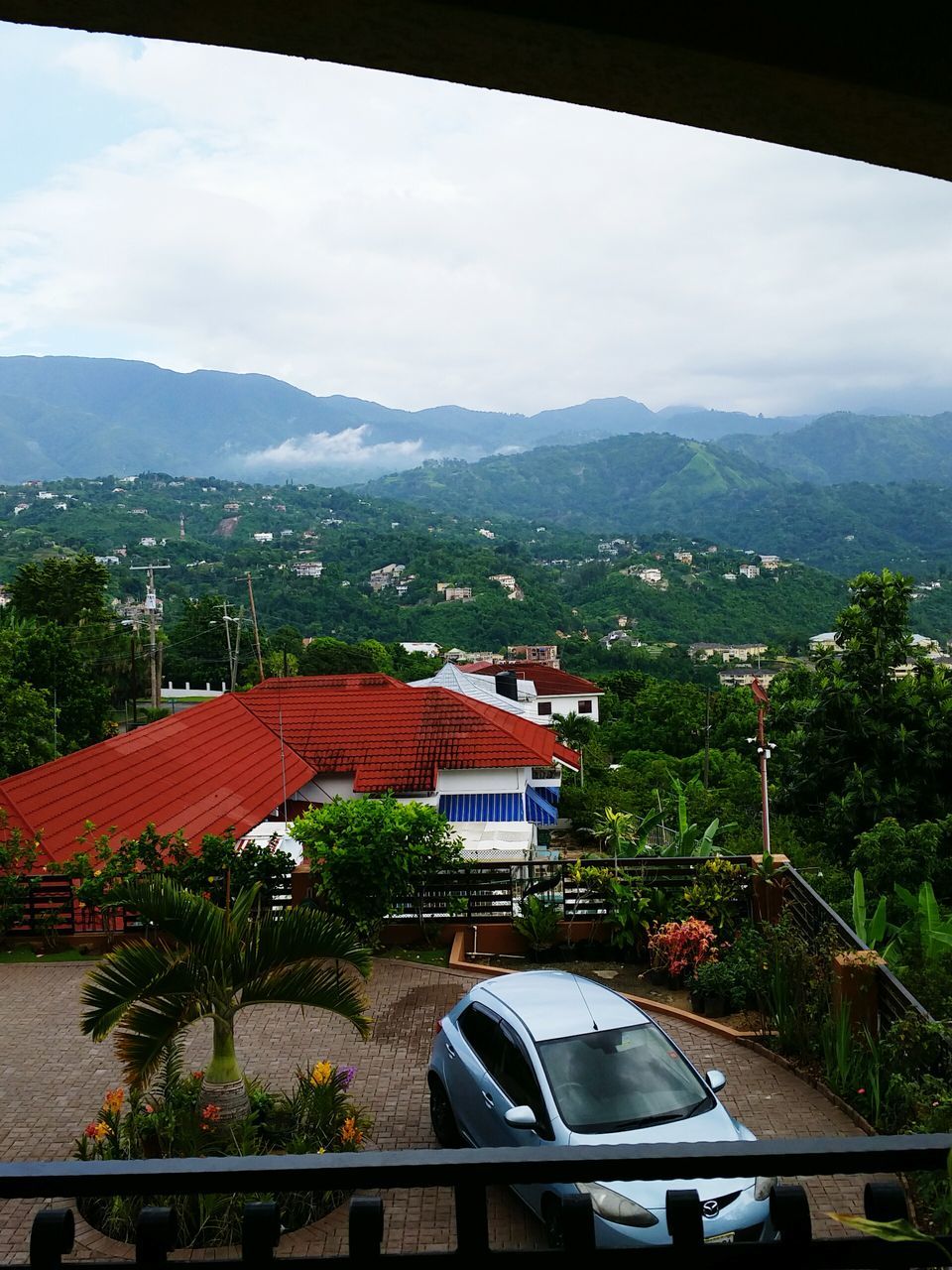 mountain, tree, architecture, built structure, sky, building exterior, mountain range, car, window, transportation, high angle view, house, road, day, roof, nature, cloud - sky, land vehicle, growth, no people