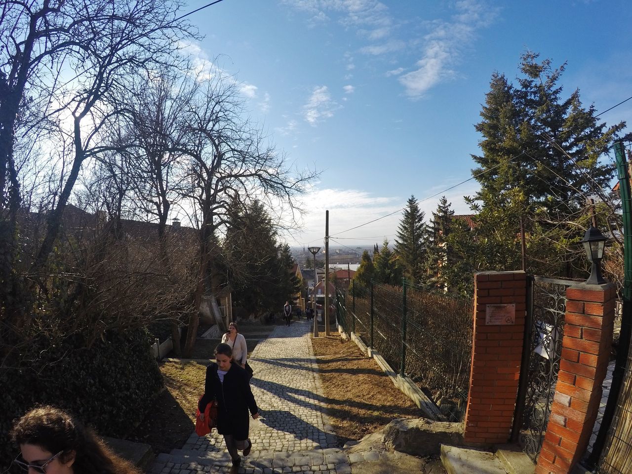 PEOPLE WALKING ON SIDEWALK AGAINST SKY