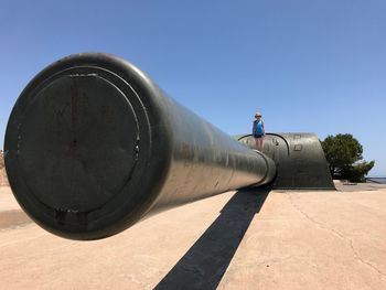 Woman standing on cannon against clear sky