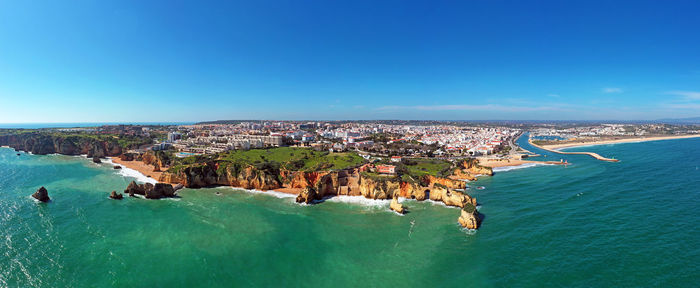 Aerial view of sea and city against clear blue sky