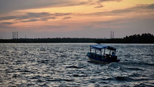 Boat sailing in sea against sky during sunset