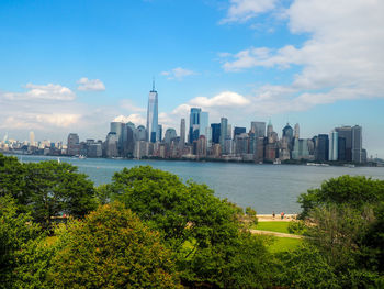 View of city at waterfront against cloudy sky