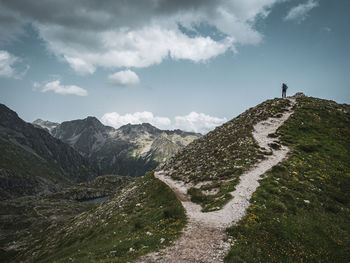 Rear view of man walking on mountain against sky