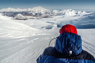 Rear view of woman on snowcapped mountain against sky