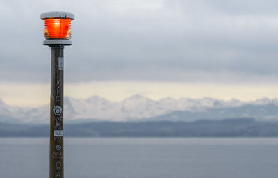 Street light by lake against sky during winter