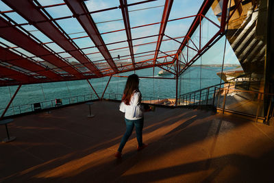 Rear view of woman standing by railing against sea