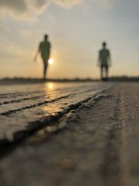 Rear view of silhouette man walking on street during sunset