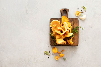 Chanterelle mushrooms on a wooden board with herbs and spices. top view