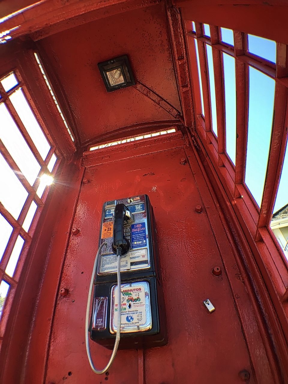 LOW ANGLE VIEW OF TELEPHONE BOOTH AGAINST WINDOW