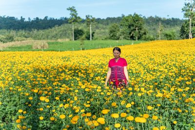 Contemplating young woman standing in marigold field
