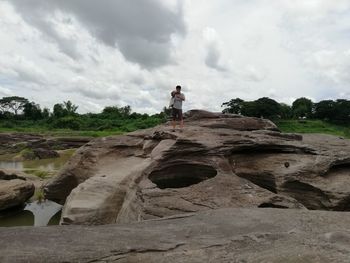 Man standing on rock against sky