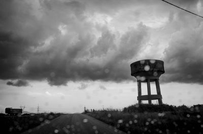 Water tower against cloudy sky seen through windshield