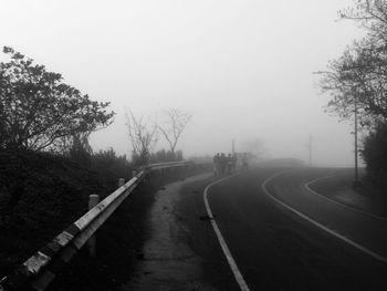 Empty road along trees and against sky