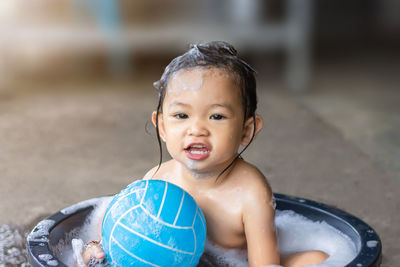 Portrait of cute baby girl sitting in tub