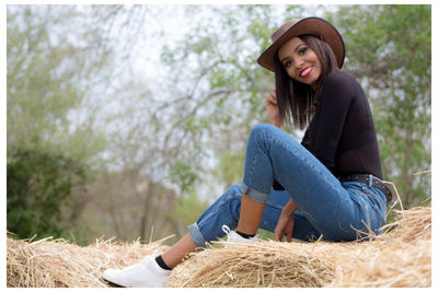 Portrait of smiling young woman sitting on field