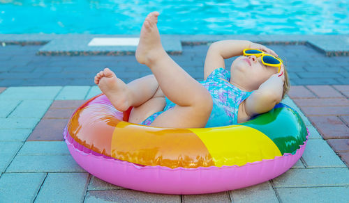 Cute baby lying on inflatable ring by swimming pool