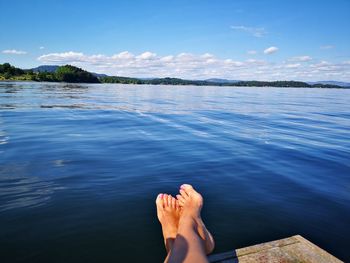 Low section of woman by lake against sky