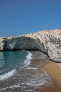 Rocks on beach against clear blue sky