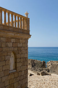 Stone wall by sea against clear sky