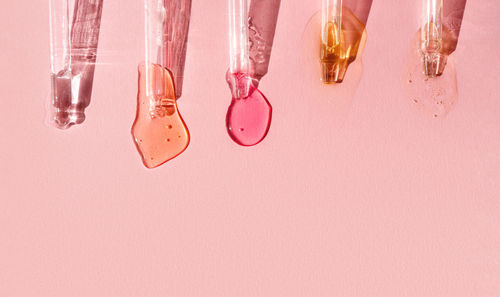 Pipettes with fluid hyaluronic acid on pink background in the sunlight. cosmetics and healthcare 