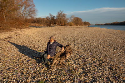 Rear view of woman with dog sitting on land