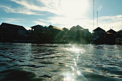 Houses by water against sky