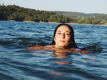 Woman looking away while swimming in sea