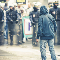 Rear view of people walking on street in city du ring a riot with police