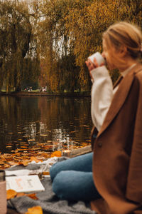 Woman sitting by lake during autumn