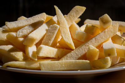 Frozen sliced potato fries on a plate, ready to fry in oil