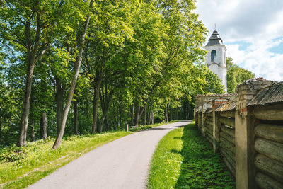 Road amidst trees and plants against sky