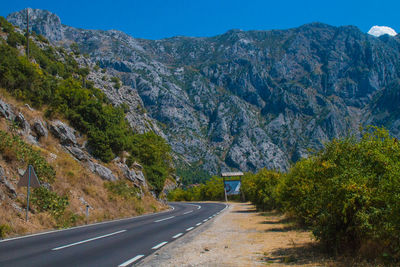 Road amidst trees and mountains against sky