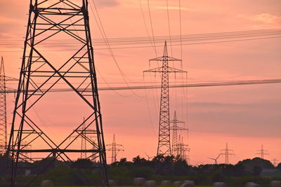 Low angle view of silhouette electricity pylon against sky during sunset