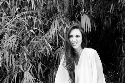 Portrait of young woman sitting against plants