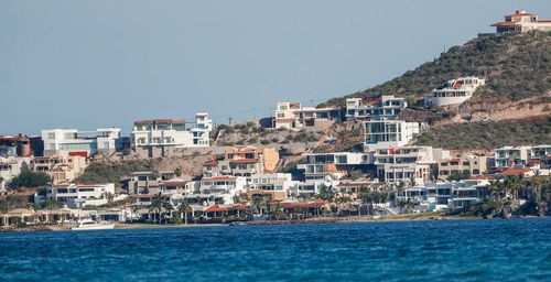 Buildings by sea against clear sky