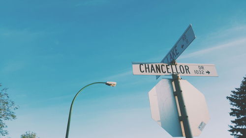 Low angle view of road sign against blue sky